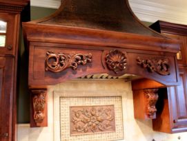 Beautiful hood above stove with wood carvings and hammered copper