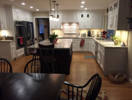 White kitchen cabinets with black island and hardwood floors
