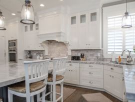 White kitchen cabinetry with gray island, back splash and counter tops