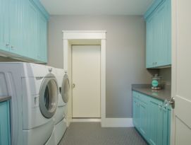 Bright aqua color on cabinetry with gray counter top in this laundry room