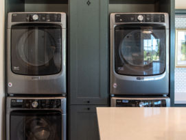 Laundry room with double stack washer and dryer with tall storage cabinetry between
