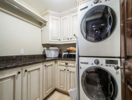 White cabinetry with dark glaze and dark granite counter tops in this laundry room