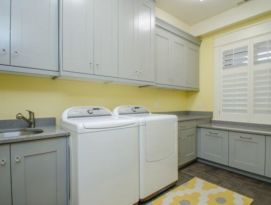 Laundry room with gray cabinetry dark gray counter tops and happy yellow walls