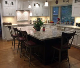 White kitchen cabinets with black island and hardwood floors