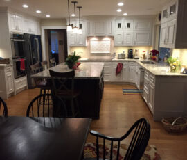 White kitchen cabinets with black island and hardwood floors
