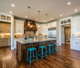White kitchen cabinetry with dark island, hood and flooring.