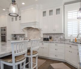 White kitchen cabinetry with gray island, back splash and counter tops