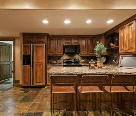 U shaped kitchenette with knotty alder cabinetry and matching appliance panels on fridge.