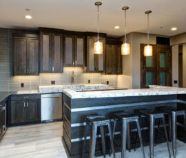 Wet bar in quarter sawn oak with gray stain. Metal mesh in top cabinets with stainless steel paneled into the bar seating area and floating shelves.