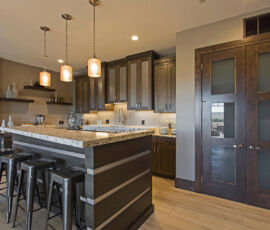 Wet bar in quarter sawn oak with gray stain. Metal mesh in top cabinets with stainless steel paneled into the bar seating area and floating shelves.