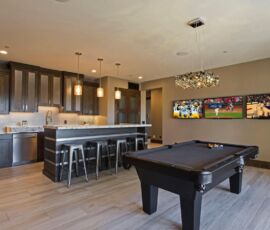 Kitchenette/bar with pool table and wall of three tvs.